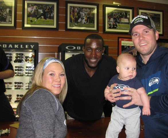 A family poses with a Seahawks player inside a sports store.