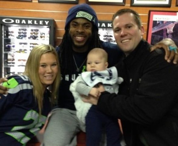 Richard Sherman posing with fans and holding a baby.